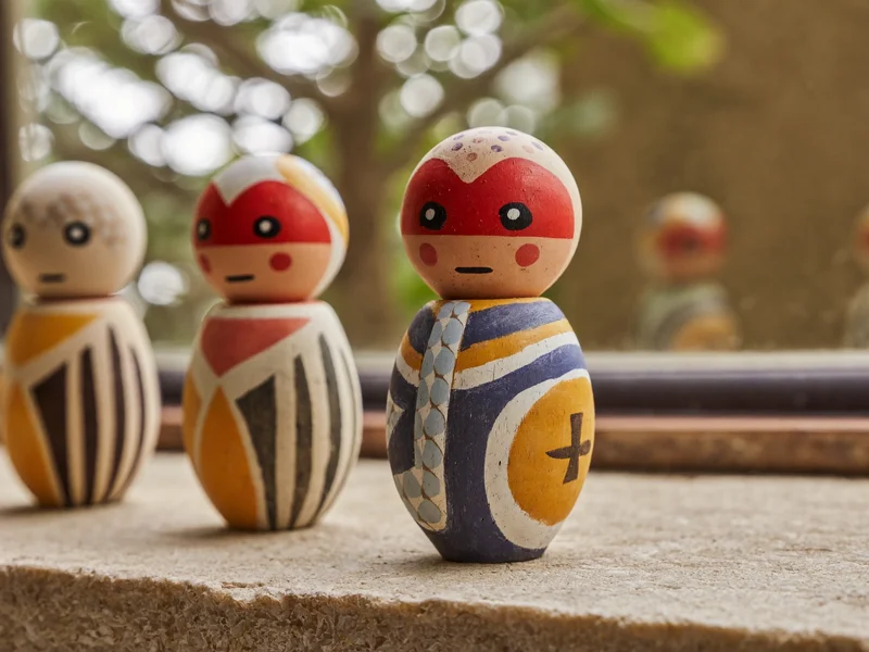 Piccole figurine souvenir in terracotta e legno dipinto allineate su un davanzale in pietra